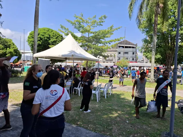 Tenda de atendimento montada na Praça da Matriz, com equipes e cidadãos ao redor, durante a ação Pop Rua Jud.