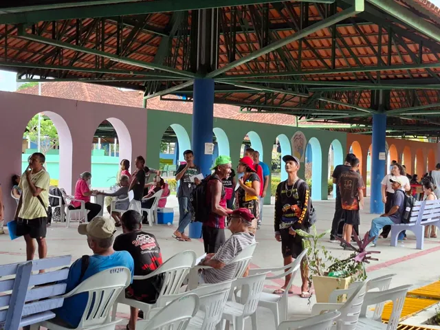 Área coberta do Parque do Idoso durante o mutirão Pop Rua Jud, com pessoas aguardando atendimento e mesas de atendimento ao fundo.