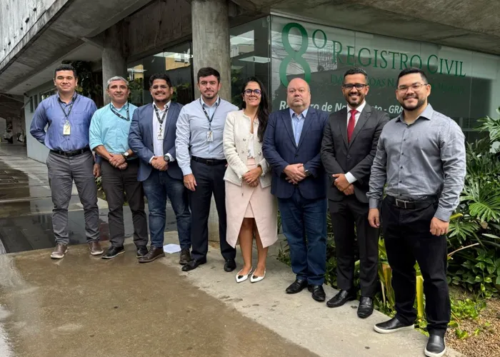 Grupo de oito pessoas em frente à fachada da antiga sede do 8º Registro Civil, entre elas o juiz Julião Lemos Sobral Júnior e o Registrador Civil Titular Miguel Jaime dos Santos Agra.