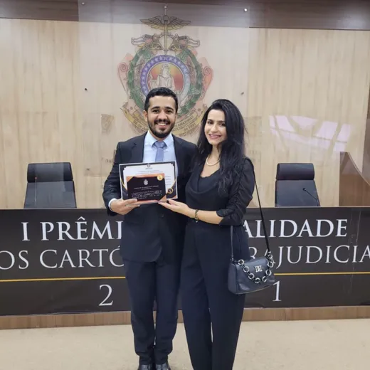 O Registrador Civil Miguel Jaime dos Santos Agra segura o certificado da categoria Ouro diante do painel do I Prêmio de Qualidade dos Cartórios Extrajudiciais 2021, na sede do Tribunal de Justiça do Amazonas.
